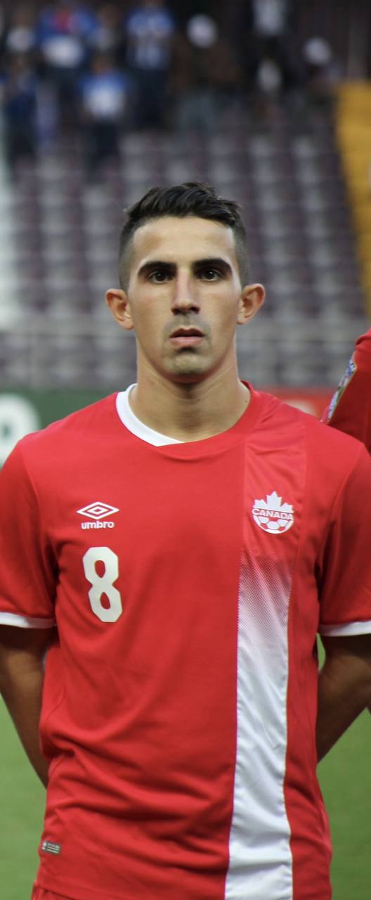 Luca in a red Canada #8 jersey, standing for the anthem.