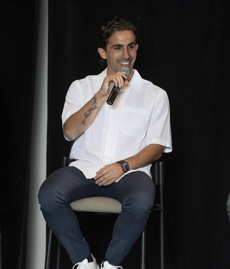 Luca Uccello seated on stage, smiling and speaking into a microphone.