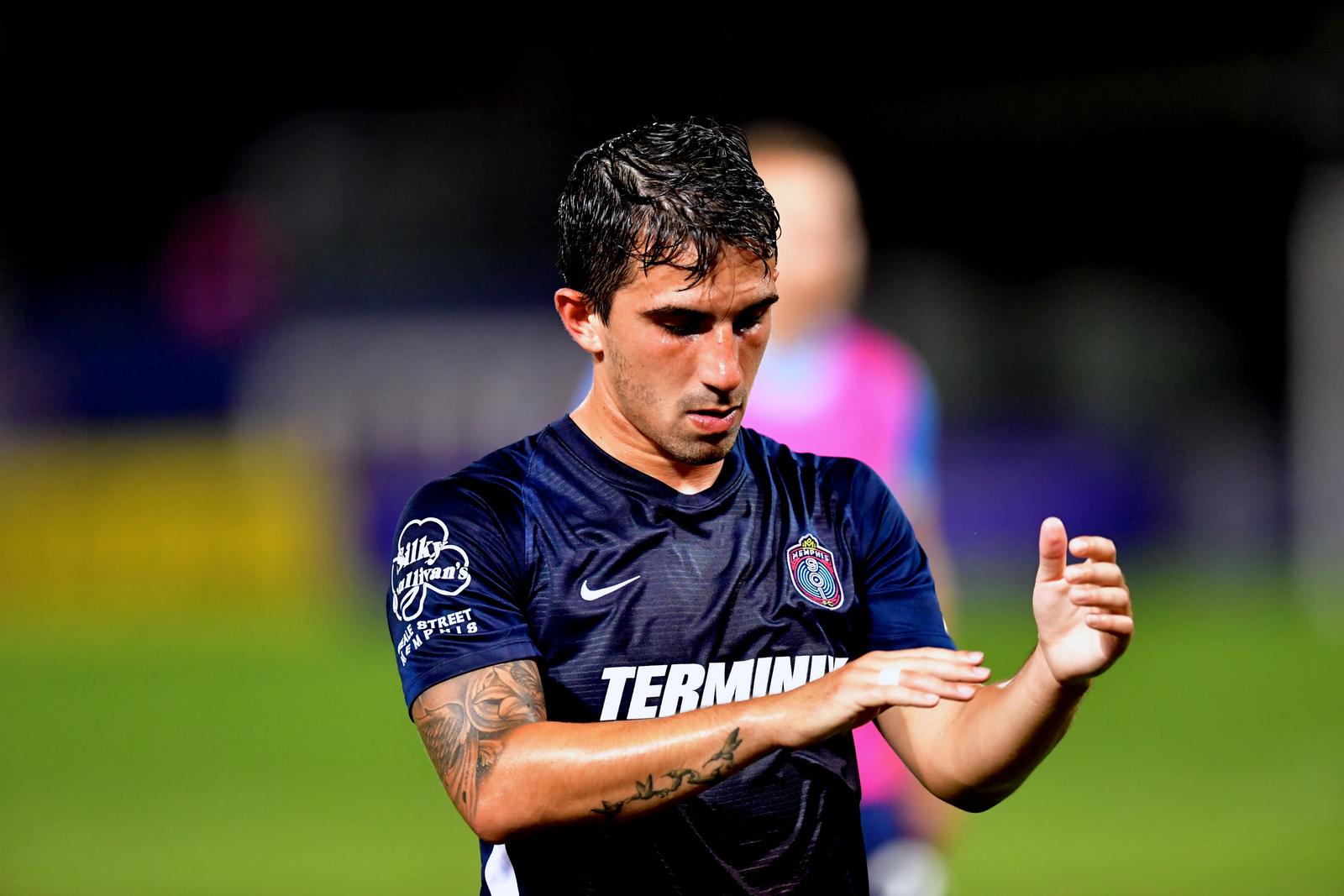 Luca in a navy kit, focused, adjusting his wrist tape.