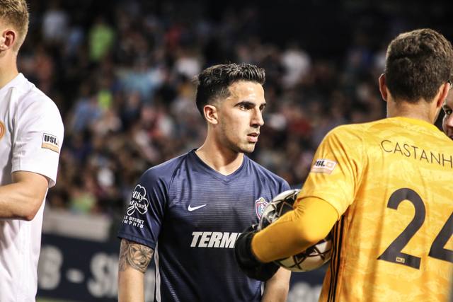 Luca in a navy kit beside a goalkeeper in yellow.
