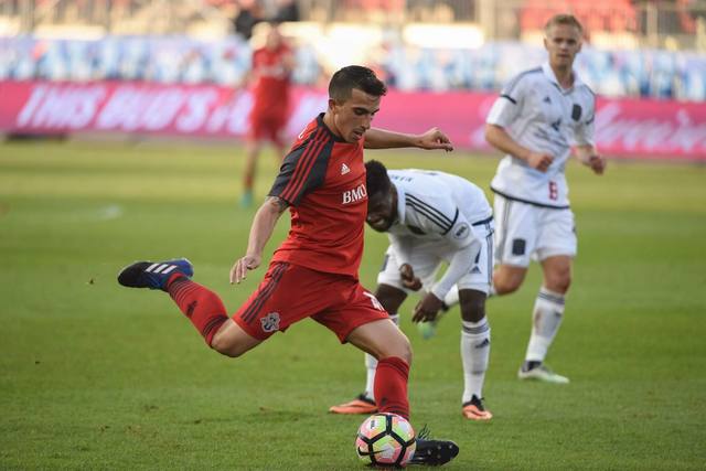 Luca in a red kit striking the ball during a match.